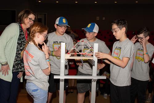 Four MESA students compete as they apply the weighted bucket to their structure.